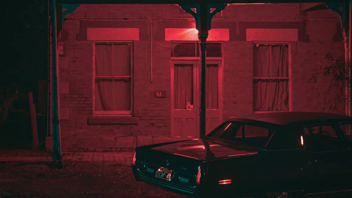 Red filtered picture of a car in front of building.