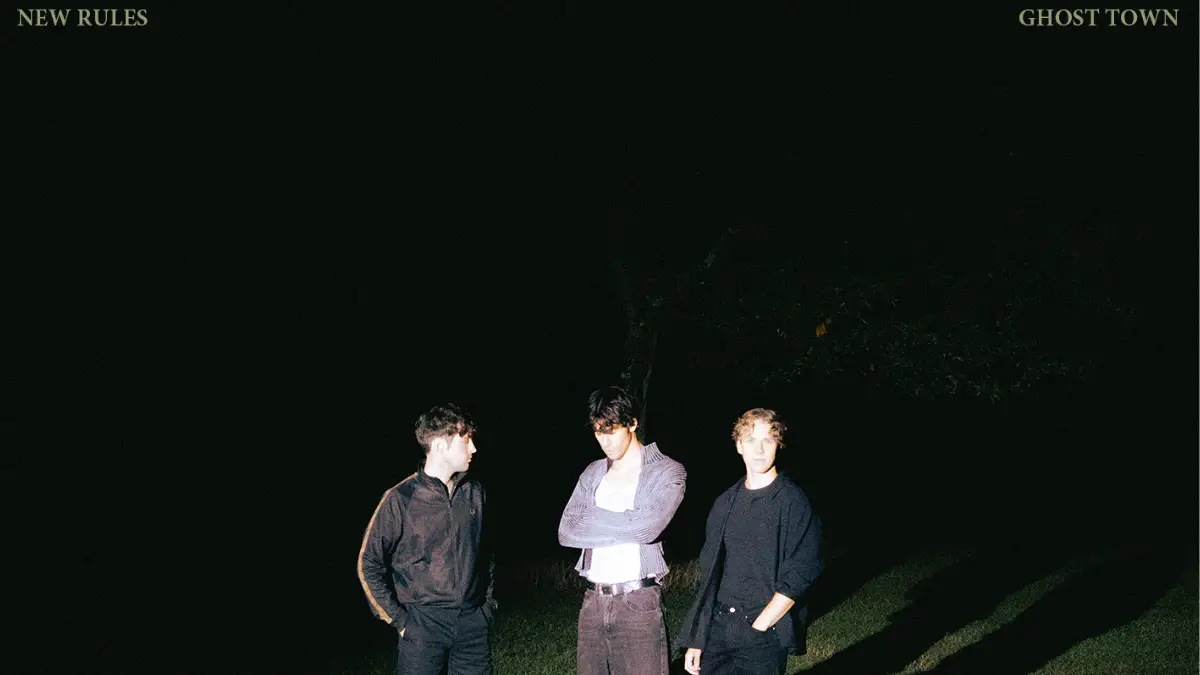Three boys standing in a dark field.