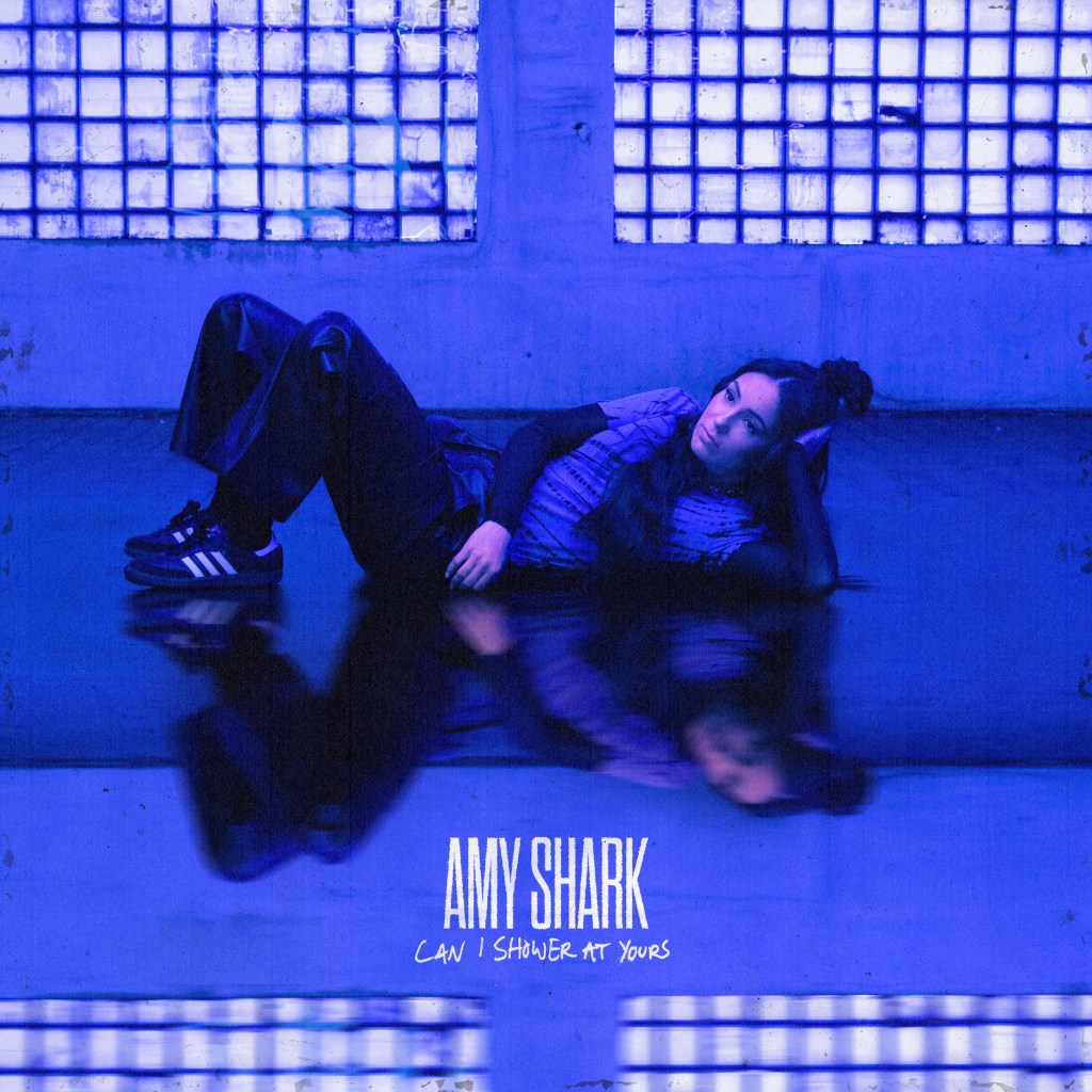 Can I Shower At Yours by Amy Shark cover art
Woman lying on the ground in an empty room washed in blue light